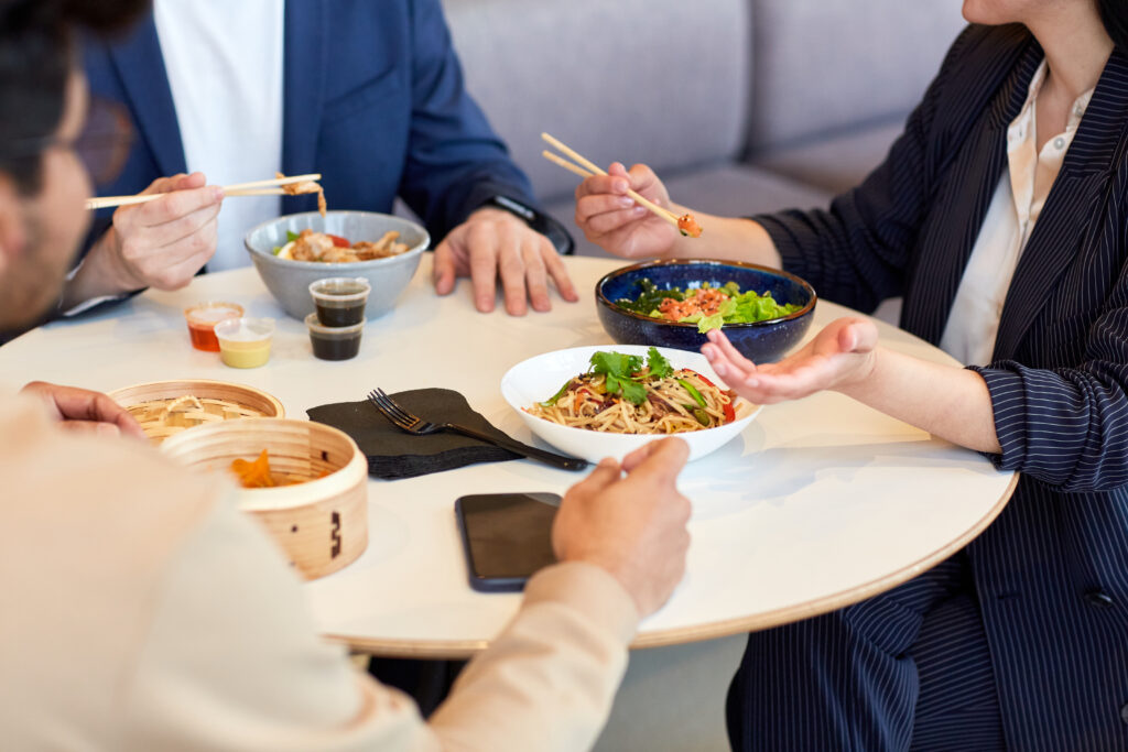 Close up of business people enjoying Asian food during business lunch in cafe